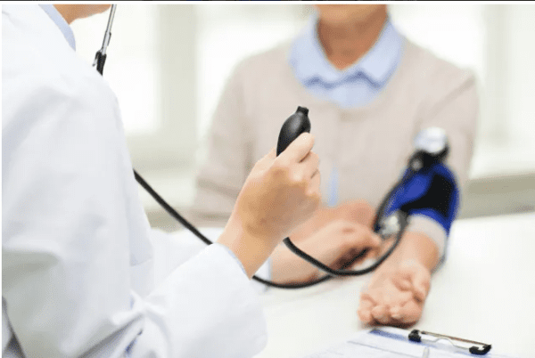 A doctor checking the blood pressure of an older person.